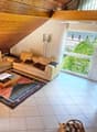 tiled floor, beige leather sofas, L-shaped sofa, wooden ceiling, coffee table, wooden rug, lamps, large windows, indoor plants, fireplace