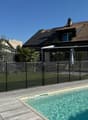 Modern house with brown roof, glass windows, black fence, swimming pool, wooden deck