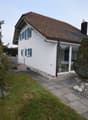 modern house, white wall, blue shutters, glass wall, solar panels on roof, paved pathway