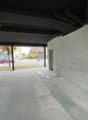 concrete wall, ceiling with beams, open parking area, person riding a bike on road
