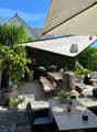 Outdoor dining area with a large table, stone benches, umbrella, plants, and decorative elements
