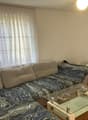 L-shaped sofa, glass coffee table, flat screen TV, white curtains, wooden floor