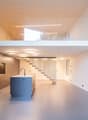 modern kitchen with island, glass railing, open staircase, wooden ceiling, white walls