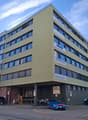 Office building, 3 floors, multiple windows, parking lot, motorcycles and cars parked