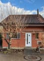 red brick small house, white door, windows with white shutters, chimney