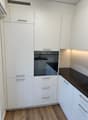 modern kitchen with white cabinets, black countertops, built-in oven, wooden floor