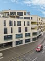 Modern multistory building, white walls, multiple garages, windows, balconies, visible mountain range