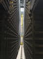 Industrial facility with large metal shelving units, yellow automated retrieval system, and a central aisle