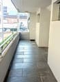 Hallway with tile flooring, white walls, and a balcony or terrace visible through the windows.