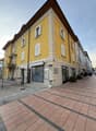 Yellow building, multiple windows, brick floor, black iron gate, balcony