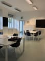 empty room, white walls, white tables, black chairs, windows, radiators, cabinets, blackboards