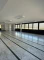 Large open space with marble flooring, floor-to-ceiling windows, and recessed lighting. The room appears to be a multipurpose space, potentially used for events or activities.