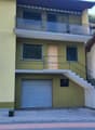2 story house, yellow exterior, metal railings, wooden door, garage, balcony