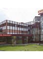 Commercial building, large glass windows, multiple floors, parking area, exterior seating, decorative signboard