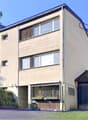 3 story house, beige exterior, large windows, front yard, garage on the right side