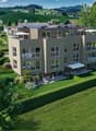 2 story building, solar panels, balcony, lush garden, green hill view