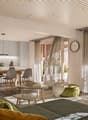 Open plan living room and dining area, wooden floor, large windows, sliding doors to balcony, modern furniture, kitchen appliances