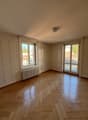 Wooden floor, white walls, double doors leading to balcony, window, radiator, city view