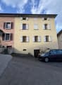 3 story house, beige walls, white shutters, car parked in front