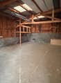 empty room, concrete floor, wooden ceiling, wooden shelves, metal ladder, small storage box