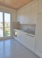 Empty kitchen with modern fittings, large window, dishwasher, washing machine, oven.