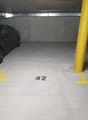 underground parking lot, with grey floor, white walls, yellow lines, car parking spot