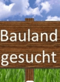 The image shows a wooden sign in a grassy field, with the text 'Bauland gesucht' which means 'Land sought' or 'Land for sale' in German.