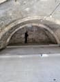 Arched ceiling, stone walls, white tile flooring, in-progress electrical wiring, arch-shaped doorways.