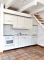 modern kitchen, white cabinets, tile flooring, staircase to upper level, stove, sink