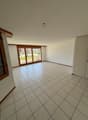 large empty room, large sliding windows, tiled floor, wooden doors