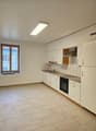 Modern, clean kitchen with white cabinetry, a tile backsplash, wooden flooring, and stainless steel appliances.