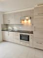 modern kitchen with wooden cabinets, black countertops, stainless steel appliances, tiled floor