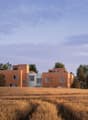 Modern architectural design, wooden exterior, multiple units, surrounded by trees and a field