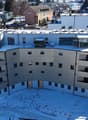Curved, multistory building, with multiple balconies, large windows, and rooftop solar panels