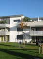 White two-story house, two balconies, green lawn, play equipment