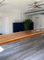 Spacious office with hardwood-style flooring, large wooden desk, ceiling fan, and a balcony or terrace visible through the window.