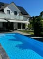 modern single family house, white walls, gray roof, solar panels, swimming pool, garden, motorcycle