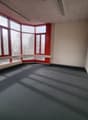 Empty room with large windows and grey carpet.