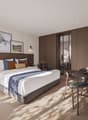 Wooden floor, large bed, bedhead with cabinets, desk, chair, lamps, table