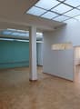 Empty room with wooden floor, white walls, glass windows, and ceiling lights