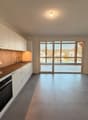 modern kitchen with white cabinets, wooden floors, gray countertops, built-in oven, sink with faucet, sliding glass doors to the terrace, white walls, recessed lighting