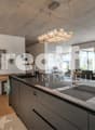 modern kitchen with large windows, wooden floor, large island with 2 sinks, chandelier, dining table, chairs