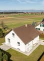 modern white house, brown roof, solar panels, large garden, driveway, surrounded by fields