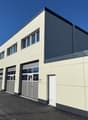 modern building, beige and gray exterior, multiple garages, windows, entrance door