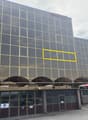 Large office building, glass windows, multiple stories, awnings over entrance, yellow highlighted window, DaKaPaint signage