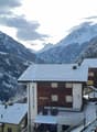 Mountain lodge house, wood paneling, covered terrace, snow on roof, balcony