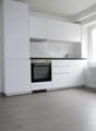 modern kitchen with white cabinets, black oven, white tiled backsplash, white radiator, wooden floor