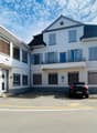 white building, three stories, parking lot, car parked in front