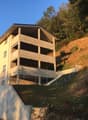 multistory building with basement, concrete facade, multiple balconies, on a slope