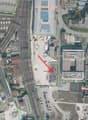 This image shows an aerial view of a commercial and industrial area. The main features visible include a large school building labeled 'Fachhochschule FHNW', a parking lot, and several other commercial and industrial buildings in the surrounding area.